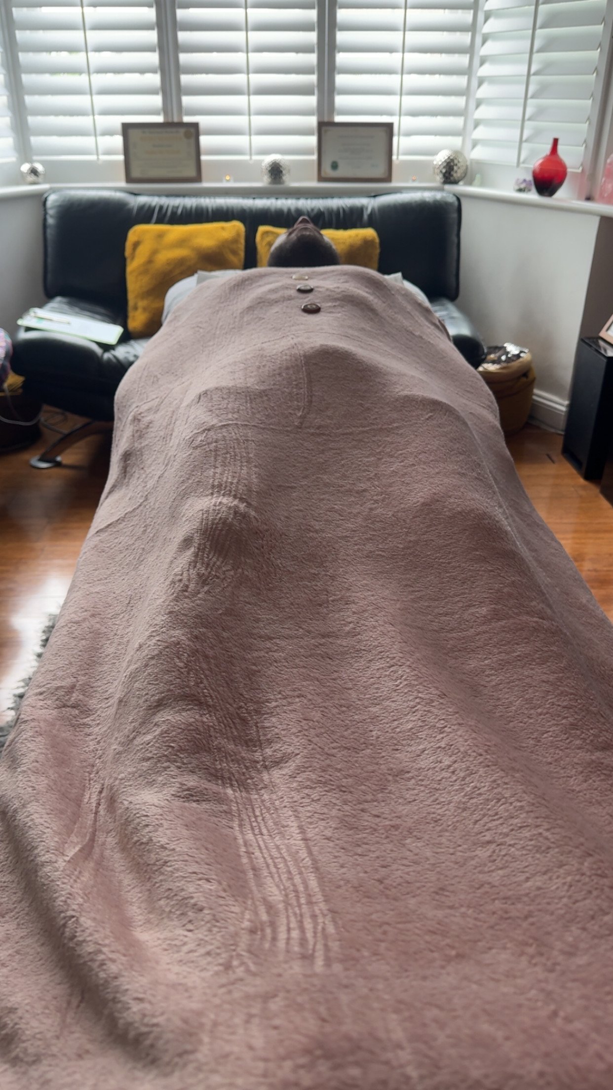A client in a meditative state laying down on the therapy couch/bed after receiving Energy healing