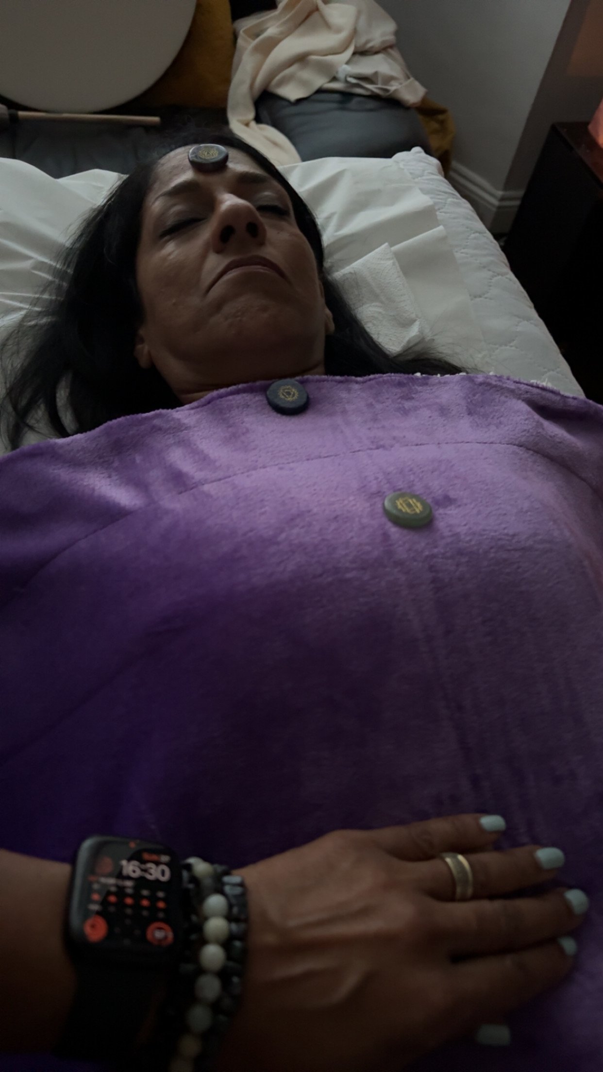 Lady Laying on Therapy Couch/bed with Crystals placed along the chakras, whilst receiving Energy healing in Enfield