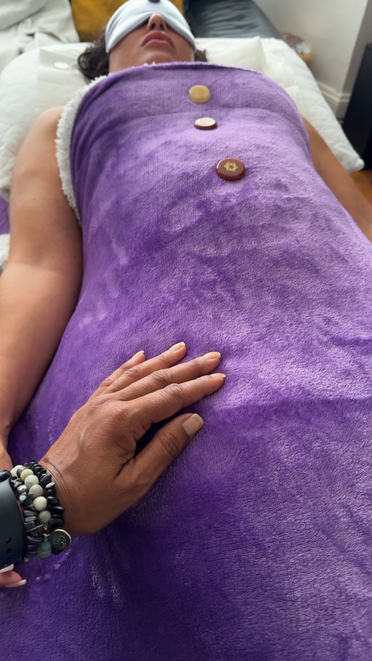 Dahni Reiki practitioner with hands on a client who is laying down on the therapy couch/bed, whilst receiving Reiki Healing