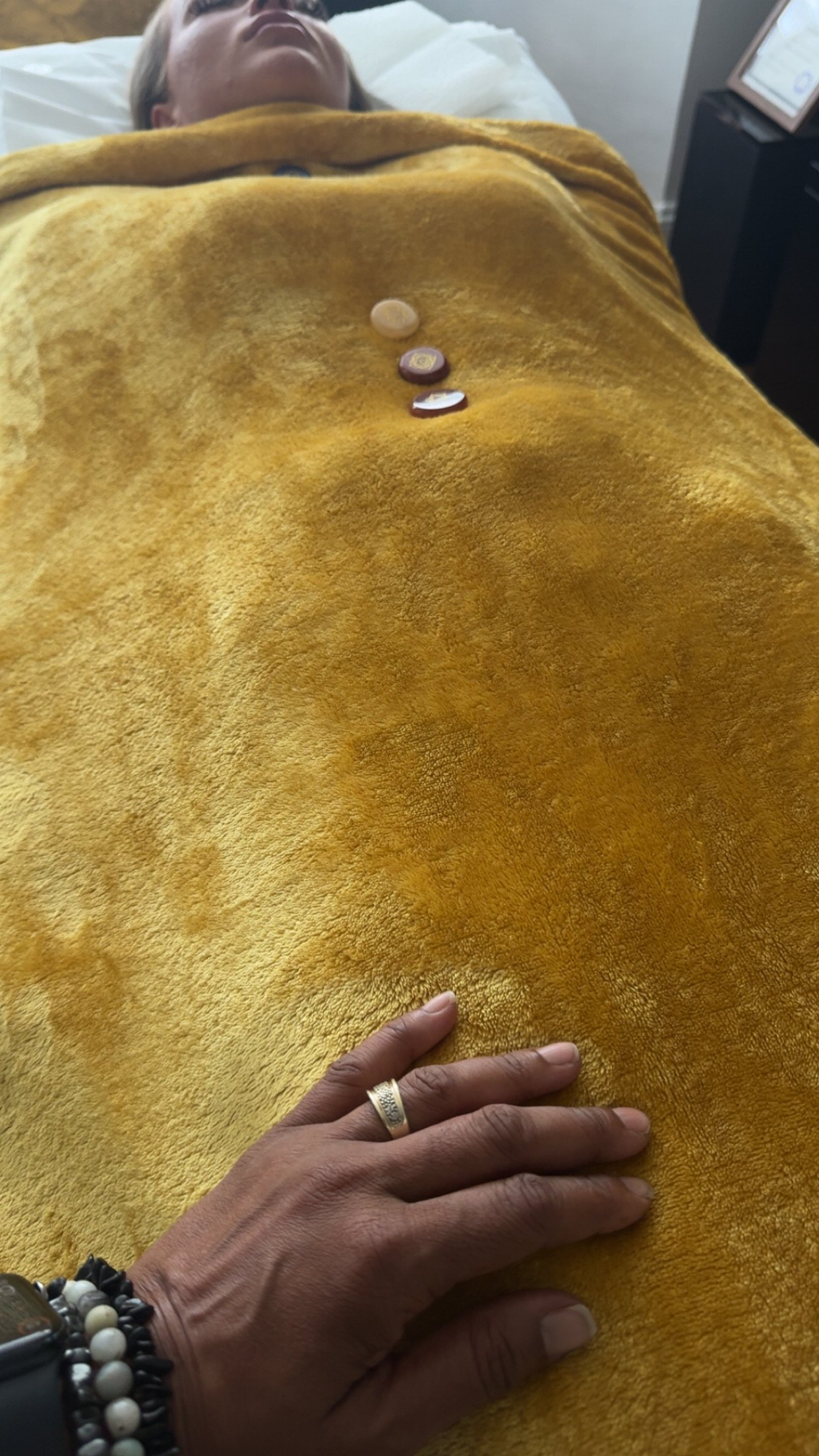 Dahni Reiki Master with her hand placed on a client who is receiving Reiki Healing, whilst laying on the Couch/Bed
