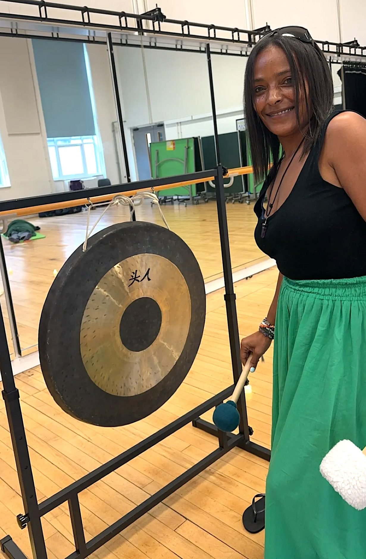 Sound Bath Enfield Dahni standing in front of a Gong at a sound Bath event.