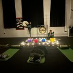 Picture of a sound bath with Shamanic Drumming, Gongs, Tibetan singing bowls, Quartz crystal sound bowls, koshi chimes and people laying on mats receiving sound therapy
